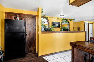 Kitchen featuring light tile patterned flooring, kitchen peninsula, and black fridge and pantry.