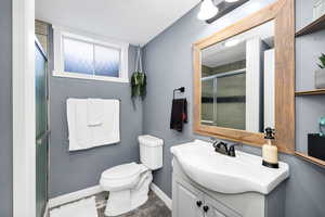 Bathroom with vanity, a shower with shower door, hardwood / wood-style floors, and toilet