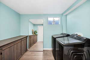 Laundry room with independent washer and dryer and light hardwood / wood-style flooring