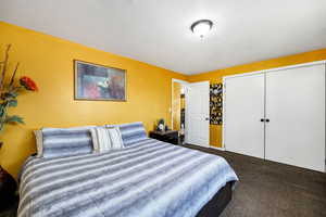 Bedroom 1 with a textured ceiling, a closet, and dark colored carpet