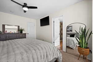 Bedroom with light colored carpet, ceiling fan, and a closet