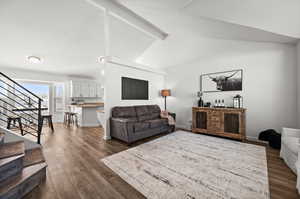 Living room with lofted ceiling with beams and dark hardwood / wood-style flooring