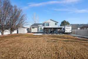 Back of house with a storage unit, a lawn, and a patio area