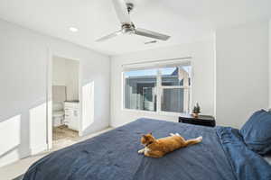 Bedroom with connected bathroom, light colored carpet, and ceiling fan