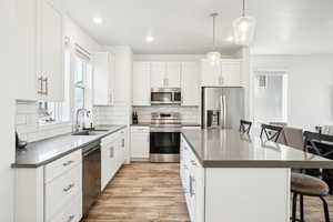 Kitchen featuring appliances with stainless steel finishes, a breakfast bar, sink, and white cabinets