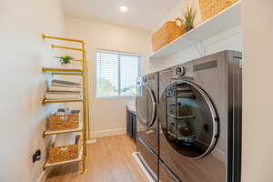 Laundry room featuring washer and dryer and light hardwood / wood-style flooring