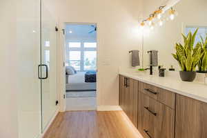 Bathroom featuring hardwood / wood-style flooring, vanity, and walk in shower