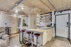 Kitchen featuring a breakfast bar, stainless steel refrigerator, sink, decorative backsplash, and kitchen peninsula