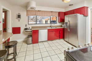 Kitchen featuring light tile patterned flooring, appliances with stainless steel finishes, and sink