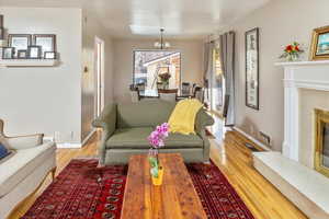 Living room featuring hardwood / wood-style flooring, a premium fireplace, and a chandelier