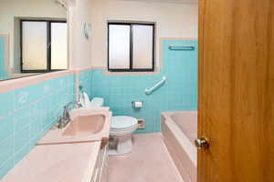 Bathroom featuring vanity, tile walls, and toilet