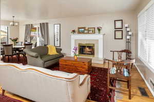 Living room with hardwood / wood-style flooring, a premium fireplace, and a chandelier