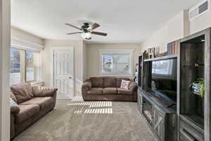 Living room featuring light carpet, ceiling fan, and a healthy amount of sunlight