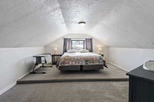 Bedroom featuring light carpet, lofted ceiling, and a textured ceiling