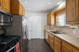 Kitchen with appliances with stainless steel finishes, sink, dark hardwood / wood-style flooring, and decorative backsplash