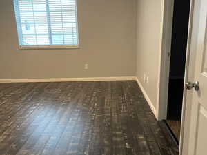 Empty room featuring dark wood-type flooring