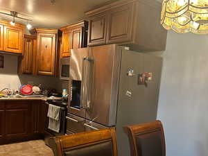 Kitchen featuring stainless steel appliances, sink, light tile patterned floors, and a textured ceiling