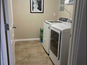 Laundry area with washing machine and dryer and light tile patterned floors