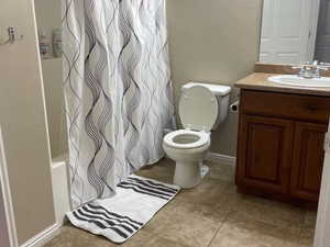 Full bathroom featuring shower / tub combo with curtain, vanity, toilet, and tile patterned flooring