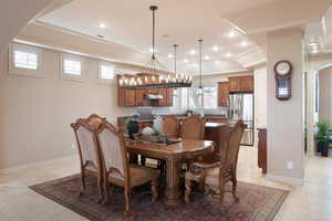 Dining room with a raised ceiling, light tile patterned floors, and a wealth of natural light