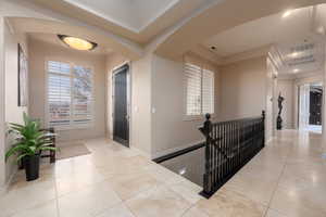 Hall with light tile patterned floors and ornamental molding