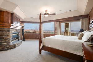 Carpeted bedroom with a fireplace, ceiling fan, and wood walls