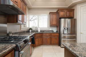 Kitchen featuring stainless steel appliances, dark stone countertops, sink, and light tile patterned floors