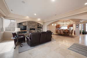 Living room with light tile patterned floors, built in features, a chandelier, and a fireplace