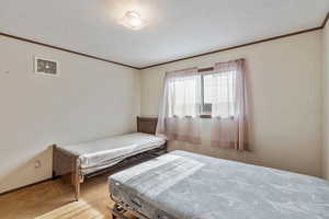 Bedroom featuring crown molding, light colored carpet, and a textured ceiling