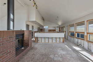 Unfurnished living room with a fireplace and high vaulted ceiling