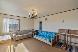 Carpeted living room with crown molding, a chandelier, and a textured ceiling