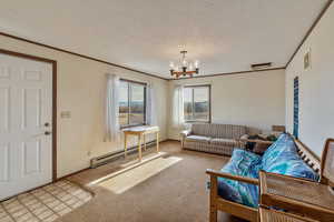 Living room with light carpet, ornamental molding, a chandelier, and baseboard heating