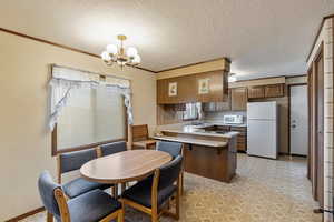 Kitchen with decorative light fixtures, sink, a notable chandelier, kitchen peninsula, and white appliances