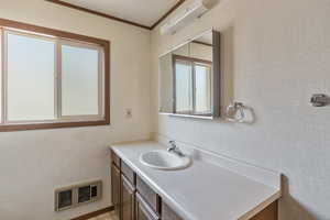 Bathroom featuring ornamental molding, vanity, and an AC wall unit