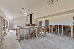 Interior space featuring rail lighting and vaulted ceiling