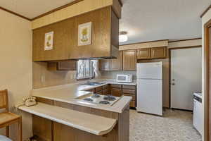 Kitchen featuring ornamental molding, a breakfast bar, white appliances, and kitchen peninsula