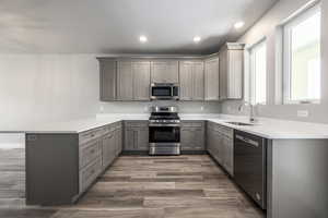 Kitchen featuring sink, gray cabinets, hardwood / wood-style floors, stainless steel appliances, and kitchen peninsula