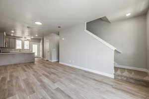 Unfurnished living room featuring an inviting chandelier and light hardwood / wood-style flooring