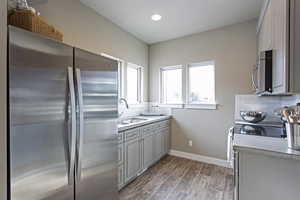 Kitchen with stainless steel appliances, gray cabinets, sink, and decorative backsplash