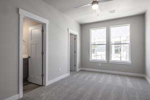 Unfurnished bedroom featuring ensuite bath, ceiling fan, and carpet