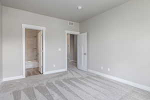 Unfurnished bedroom with light carpet and ensuite bathroom