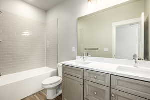 Full bathroom featuring vanity, tiled shower / bath, hardwood / wood-style floors, and toilet