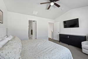 Carpeted bedroom featuring ensuite bath, vaulted ceiling, and ceiling fan