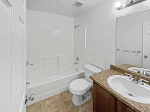 Full bathroom with shower / tub combination, vanity, toilet, tile patterned floors, and a textured ceiling