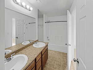 Bathroom featuring vanity, tile patterned flooring, shower / tub combination, and a textured ceiling