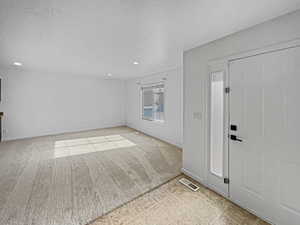 Carpeted foyer with a textured ceiling