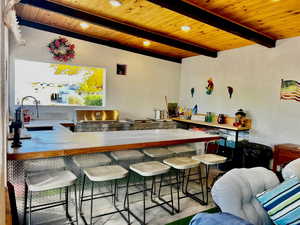 Bar featuring sink, wooden ceiling, and beam ceiling