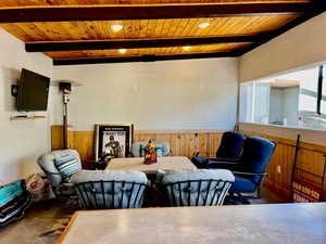 Dining room featuring wood ceiling, wooden walls, and beam ceiling