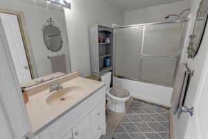 Full bathroom with toilet, vanity, combined bath / shower with glass door, and tile patterned flooring