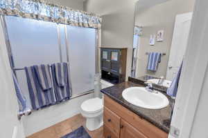 Full bathroom featuring toilet, tile patterned floors, bath / shower combo with glass door, and vanity